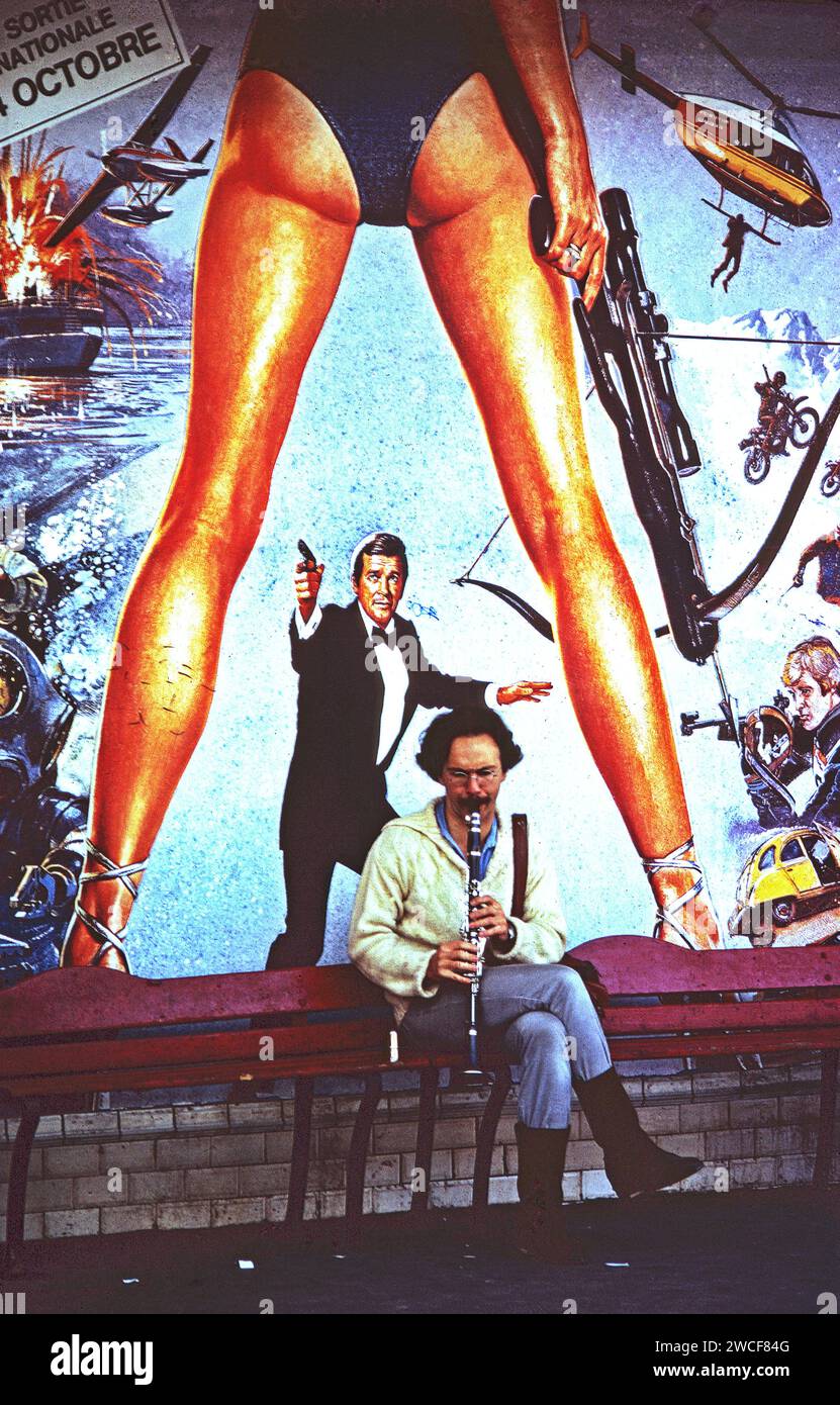 Clarinettiste pratiquant sur un quai de métro parisien sur fond d'une grande affiche de film pour le film de James Bond de 1981, pour vos yeux seulement. Banque D'Images