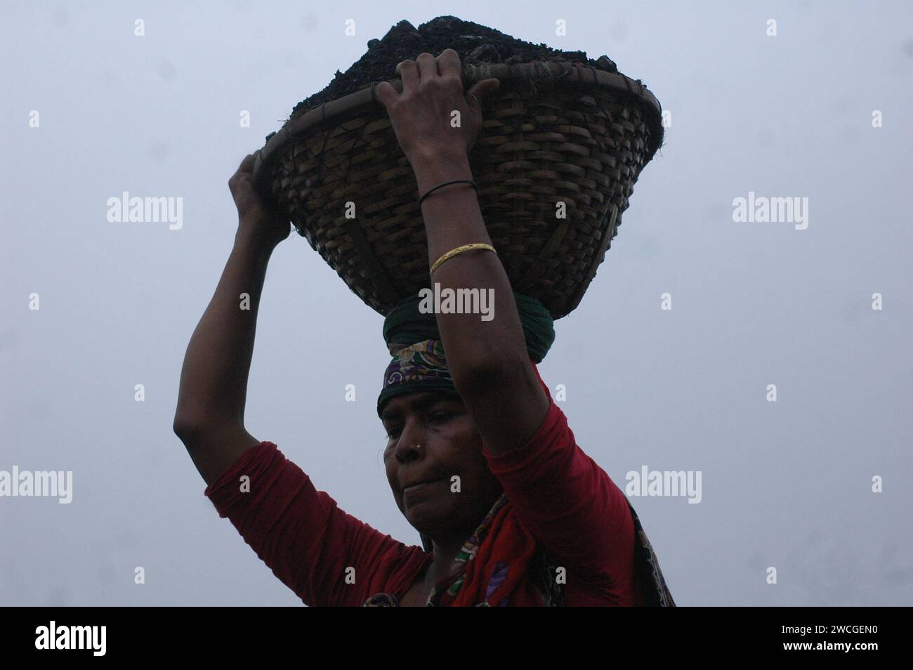 Dhaka, Bangladesh. 16 janvier 2024. Une travailleuse porte un panier de charbon sur la tête dans un marché de gros de charbon à Dhaka. (Image de crédit : © MD Mehedi Hasan/ZUMA Press Wire) USAGE ÉDITORIAL SEULEMENT! Non destiné à UN USAGE commercial ! Banque D'Images