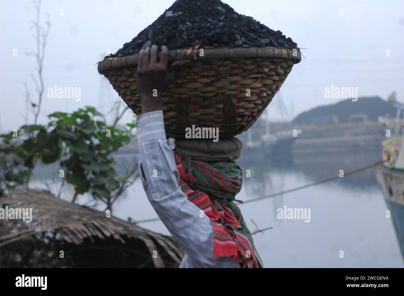 Dhaka, Bangladesh. 16 janvier 2024. Un ouvrier porte un panier de charbon sur sa tête dans un marché de gros de charbon à Dhaka. (Image de crédit : © MD Mehedi Hasan/ZUMA Press Wire) USAGE ÉDITORIAL SEULEMENT! Non destiné à UN USAGE commercial ! Banque D'Images