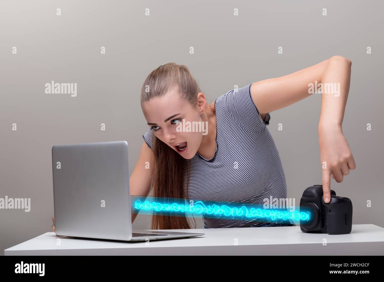 Jeune femme transfère des fichiers de l'appareil photo à l'ordinateur portable dans badass, cool manière. L'énergie quantique interdimensionnelle des gravitons positroniques exploite le g du gizmo Banque D'Images