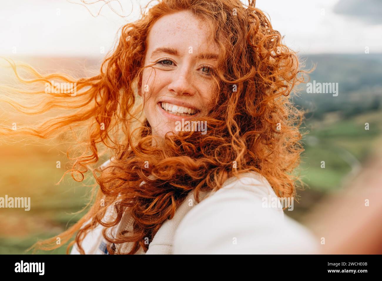 Heureuse femme voyageur dans une veste blanche et sac à dos orange voyageant dans les montagnes et prenant des photos par téléphone dans Peak District. Style de vie touristique local Banque D'Images