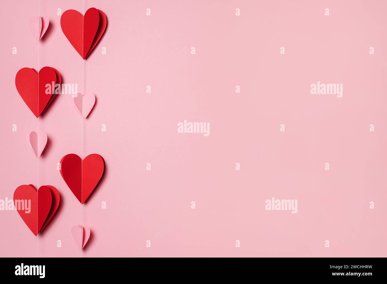 Guirlande de papier de coeurs rouges et roses sur fond rose, espace de copie. Bonne Saint Valentin. carte de voeux Banque D'Images