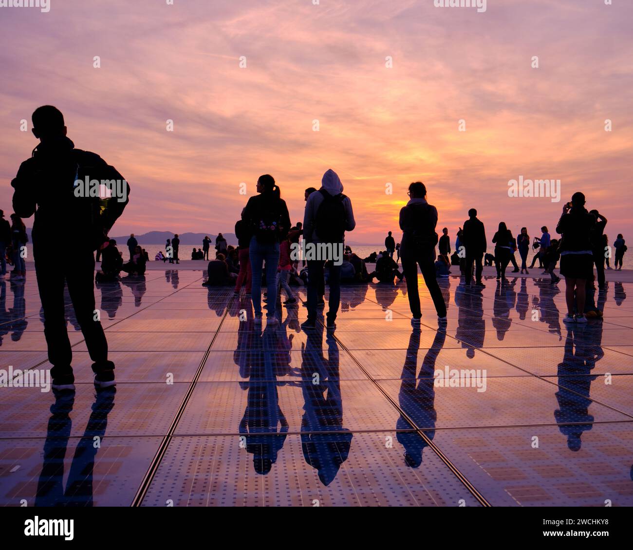 Silhouette de personnes contre un coucher de soleil orange au monument de salutation au soleil. Zadar, Croatie Banque D'Images