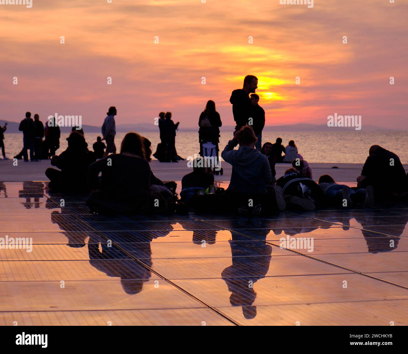 Silhouette de personnes contre un coucher de soleil orange au monument de salutation au soleil. Zadar, Croatie Banque D'Images