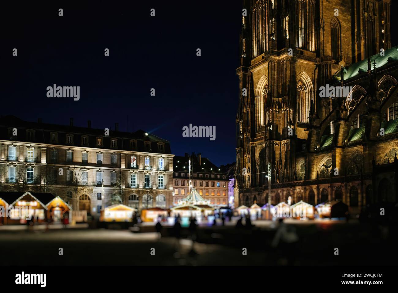 Une vue nocturne d'un marché extérieur animé à côté d'une cathédrale gothique de Strasbourg, brillamment illuminée sous le ciel étoilé Banque D'Images
