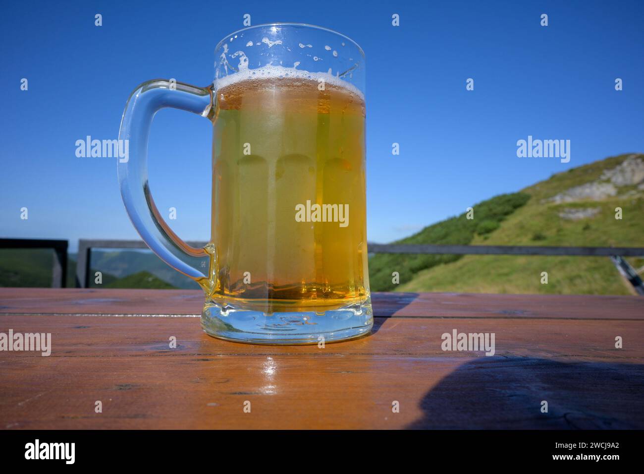un verre de bière sur une table avec vue sur les montagnes. Banque D'Images