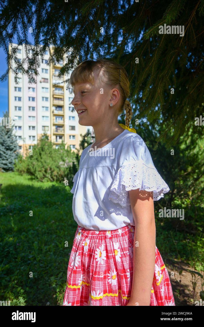 fille de 7 ans en costume et tresse tressée avec un arc jaune, photographiée à partir du profil. Banque D'Images