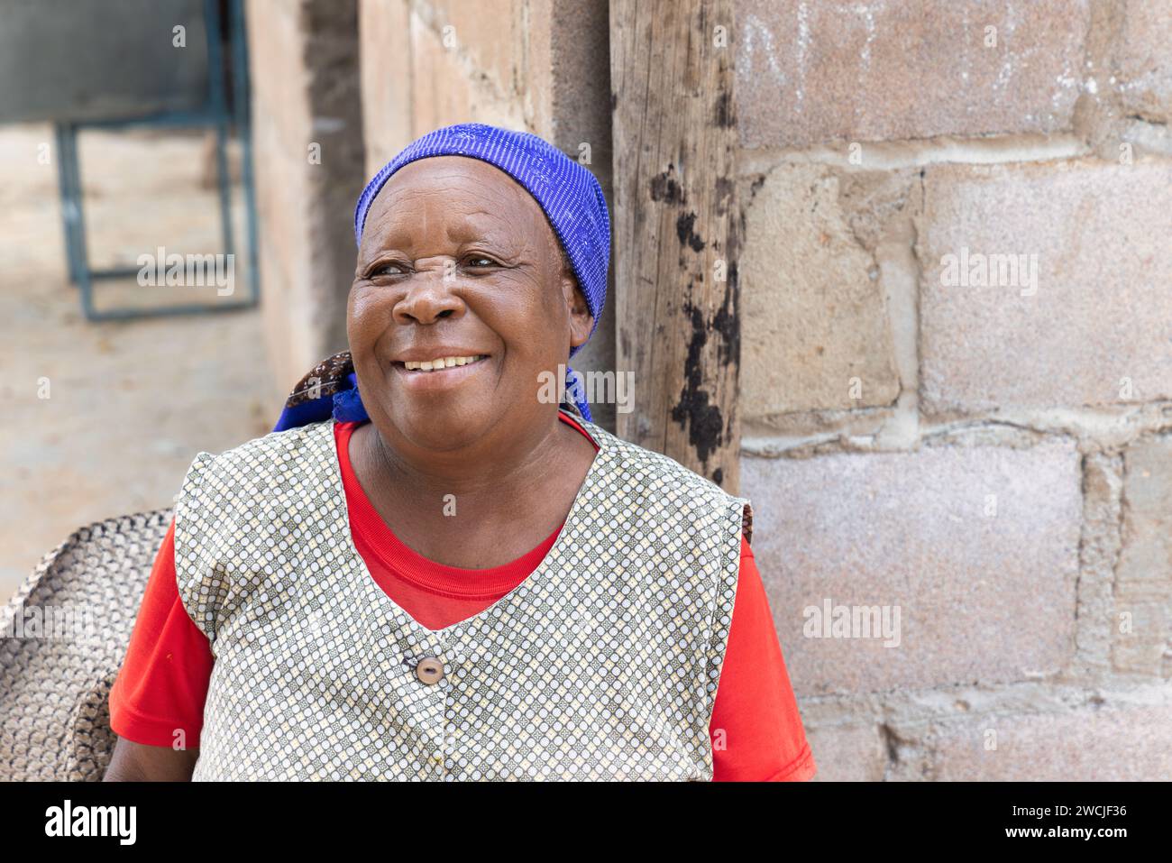 portrait d'une femme aînée africaine heureuse dans le village, la maison informelle en arrière-plan Banque D'Images