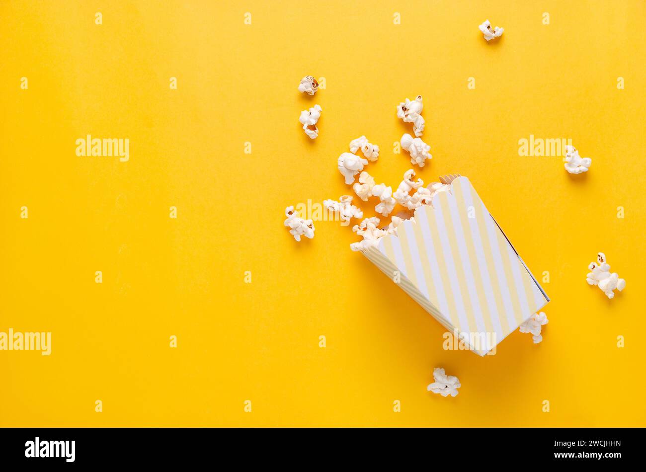 Un seau rayé de pop-corn sur fond jaune, vue de dessus et espace de copie. Banque D'Images