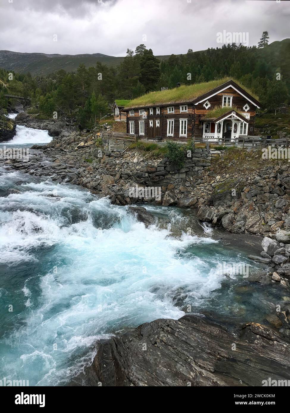 Vue d'une maison traditionnelle en bois couverte de mousse avec un ruisseau de montagne en rage en Norvège Banque D'Images