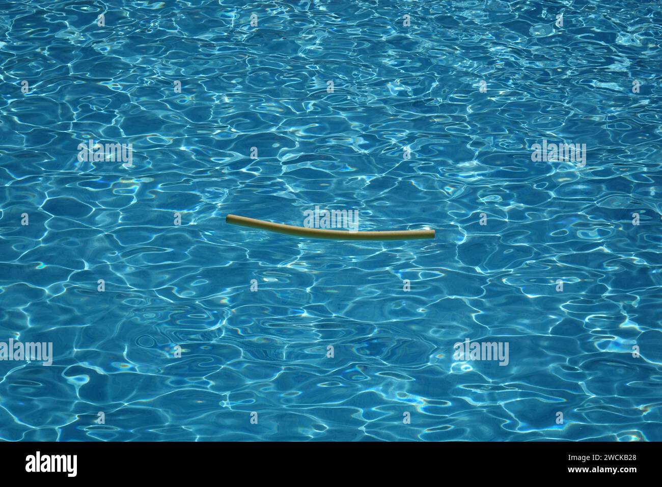 Reflets dans une piscine sans personne et seulement une nouille de piscine flottant dedans, créant un motif abstrait Banque D'Images