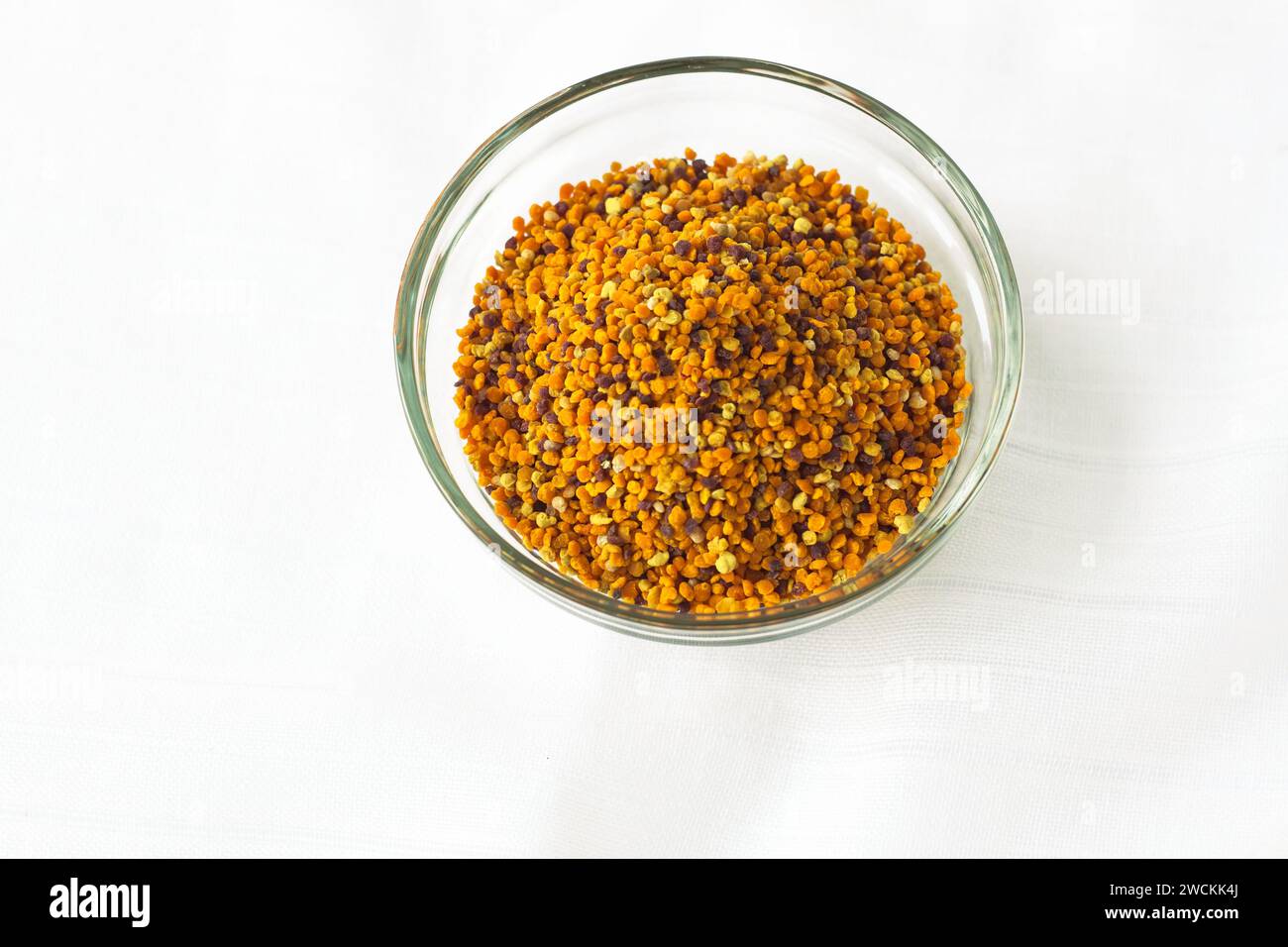 Granules de pollen d'abeille dans un bol en verre sur fond blanc.Superfood, mélange de nectar de fleur, enzymes, miel, sécrétions de cire. Nutriments, acides aminés, l Banque D'Images