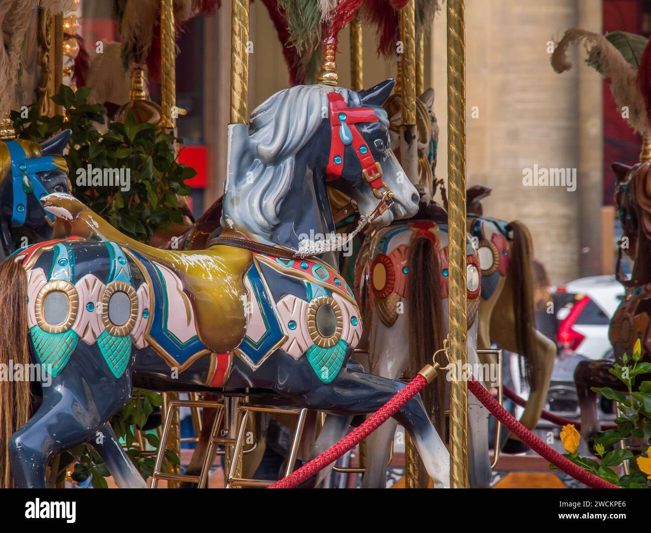 Un cheval de manège festif en couleur, orné de décorations de Noël et de verdure luxuriante, est exposé à l'extérieur Banque D'Images