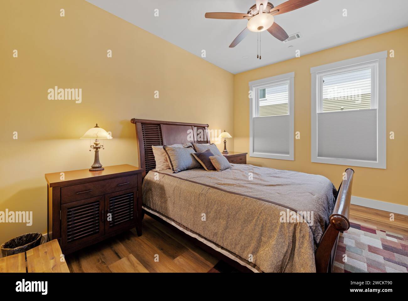 Parquets et murs en bois ornés de garnitures blanches dans une chambre, dotée d''un cadre de lit et d''un ventilateur de plafond Banque D'Images