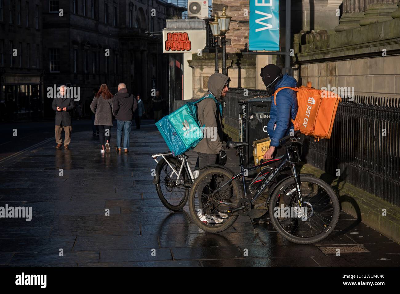 Messagers de livraison de nourriture à vélo discutant sur Nicolson Street, Édimbourg, Écosse, Royaume-Uni. Banque D'Images