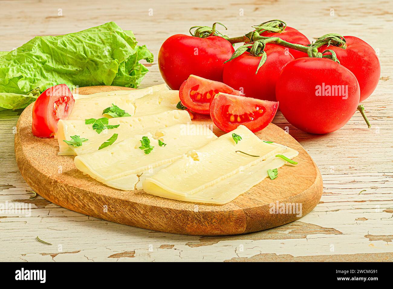 Fromage en tranches, tomates et laitue soigneusement disposés sur une planche à découper Banque D'Images