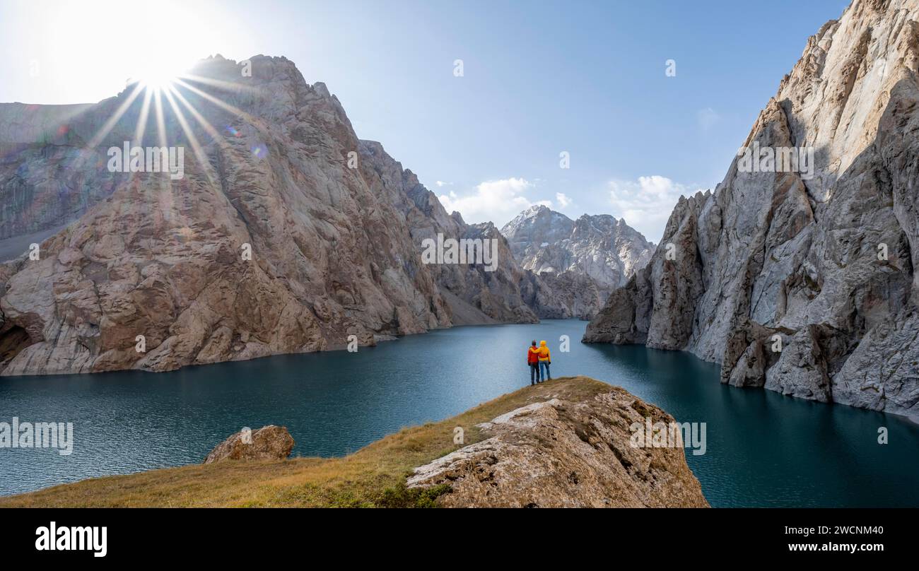 Couple au lac de montagne bleu entre les pics rocheux escarpés de montagne, Sun Star, Kol Suu Lake, Sary Beles Mountains, province de Naryn, Kirghizistan Banque D'Images