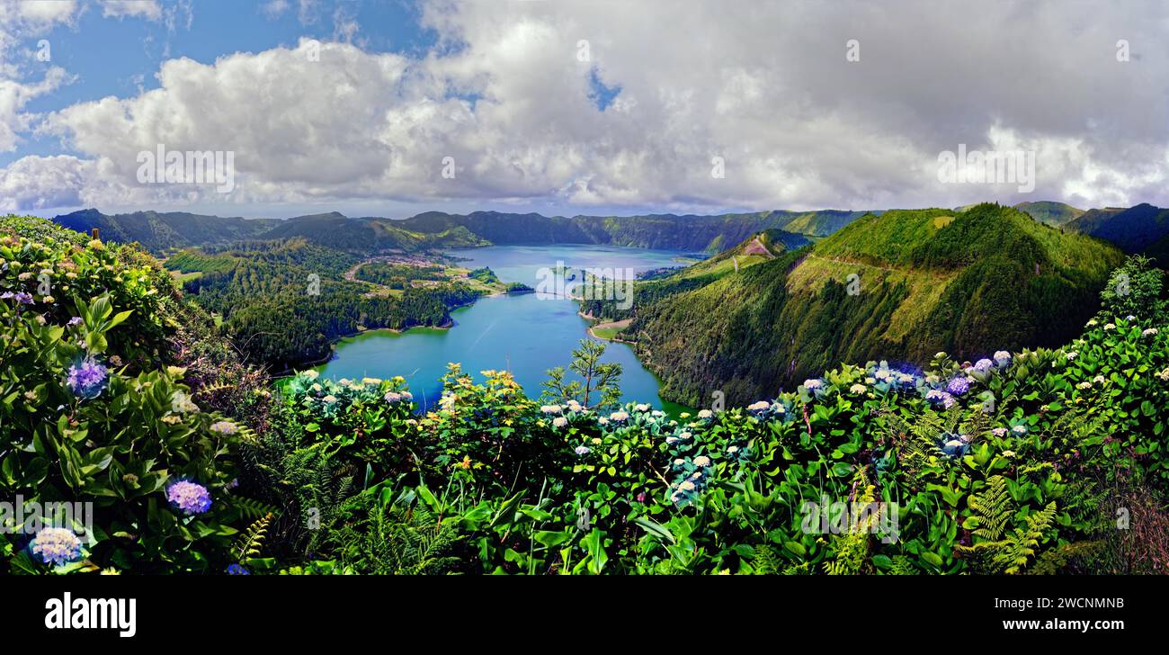 Vue panoramique pittoresque sur les lacs de cratère Lagoa Verde et Lagoa Azul entourés de bords de cratère verts et d'hortensia fleurie sous un ciel clair Banque D'Images