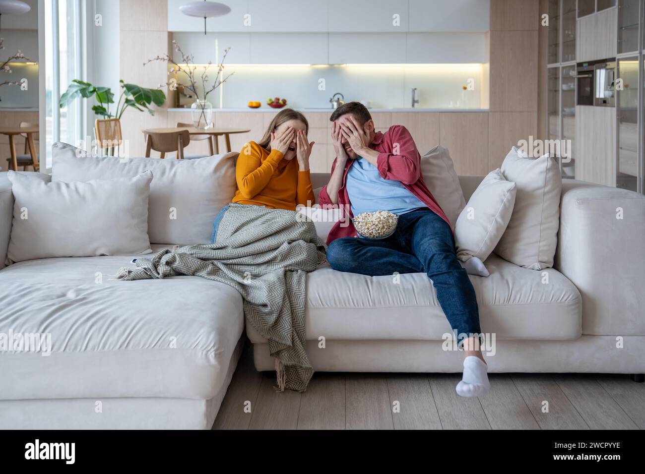 Homme effrayé femme fermant les visages avec les mains regardant des films d'horreur mangeant du pop-corn. Home Cinema Banque D'Images