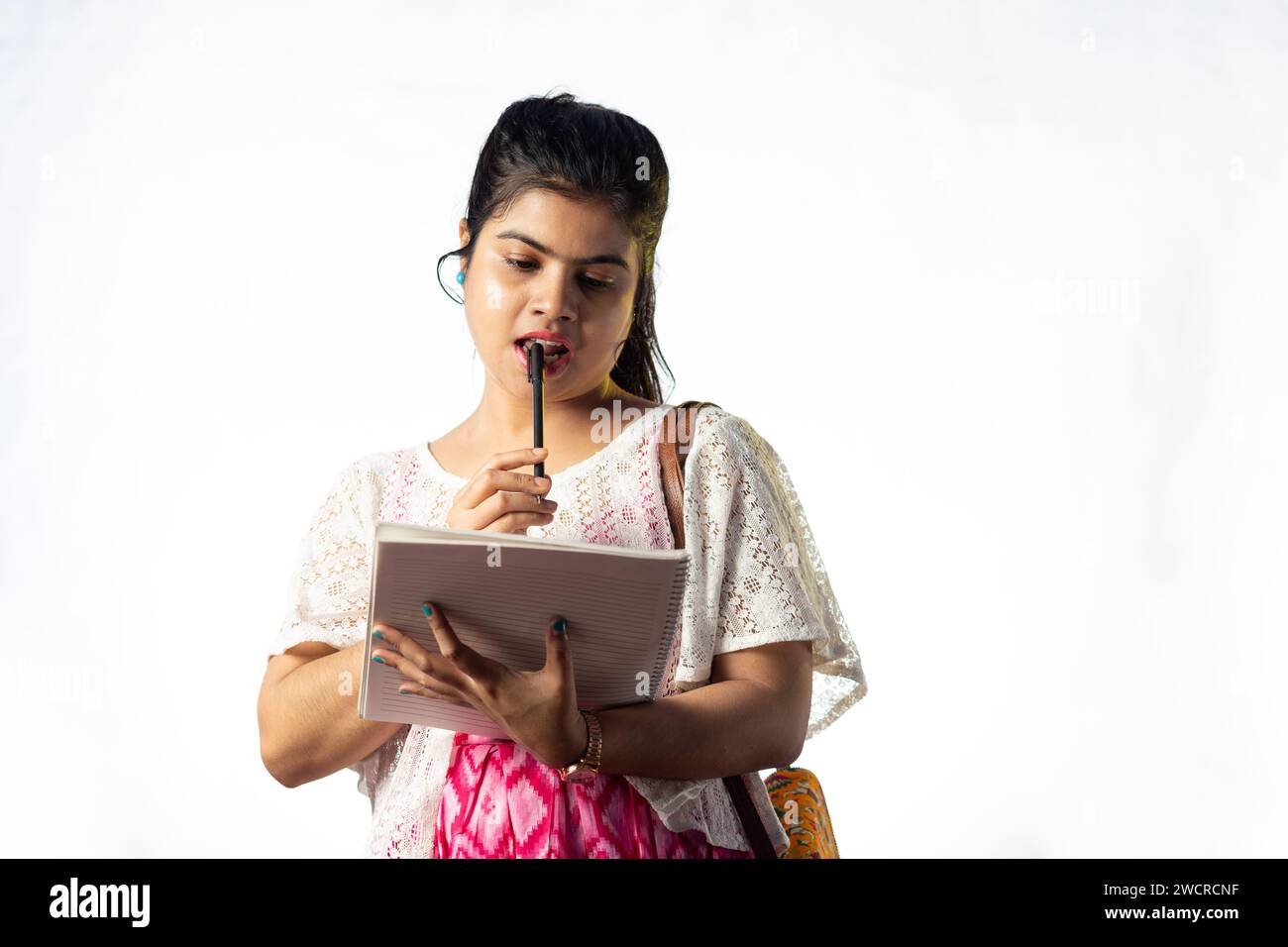 Une jolie jeune fille indienne prenant des notes sur fond blanc Banque D'Images