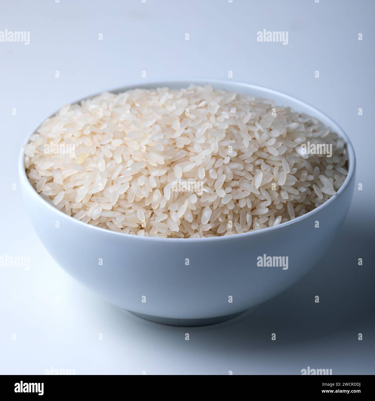 Riz dans un bol sur fond blanc. Gros plan mise au point sélective. Banque D'Images