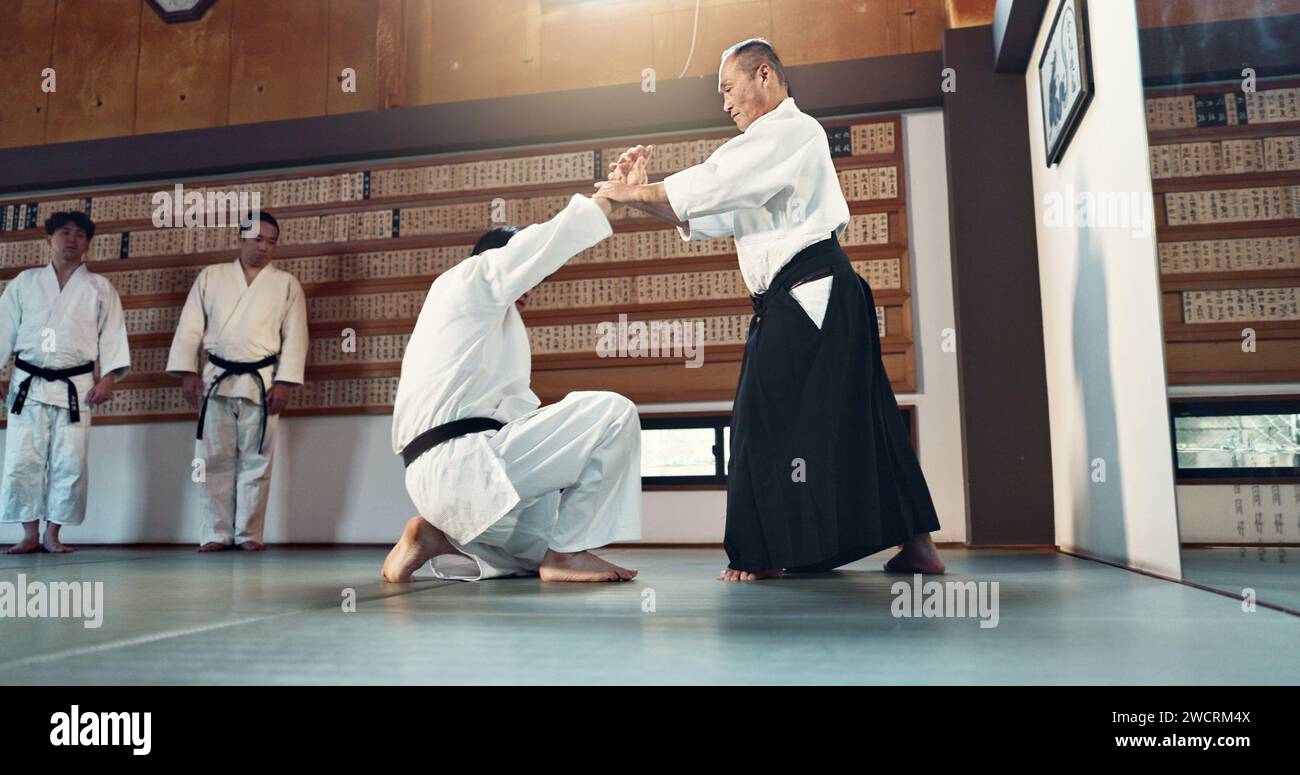 Aïkido, sensei et étudiants japonais avec discipline, fitness et action en classe pour la défense ou la technique. Arts martiaux, personnes ou combats avec Banque D'Images