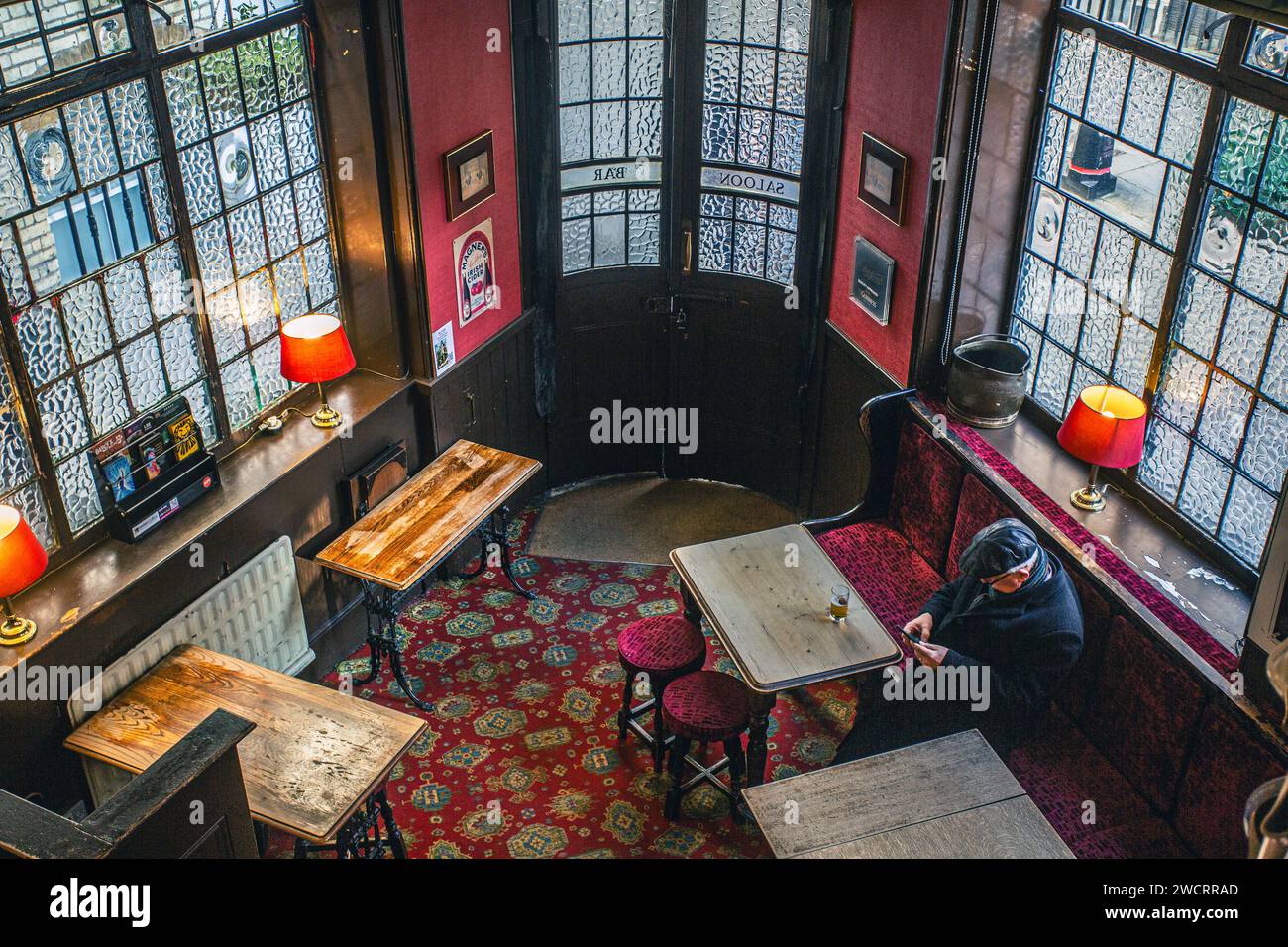 Homme mûr regardant son téléphone intelligent dans un pub britannique traditionnel à Londres , Royaume-Uni . Banque D'Images