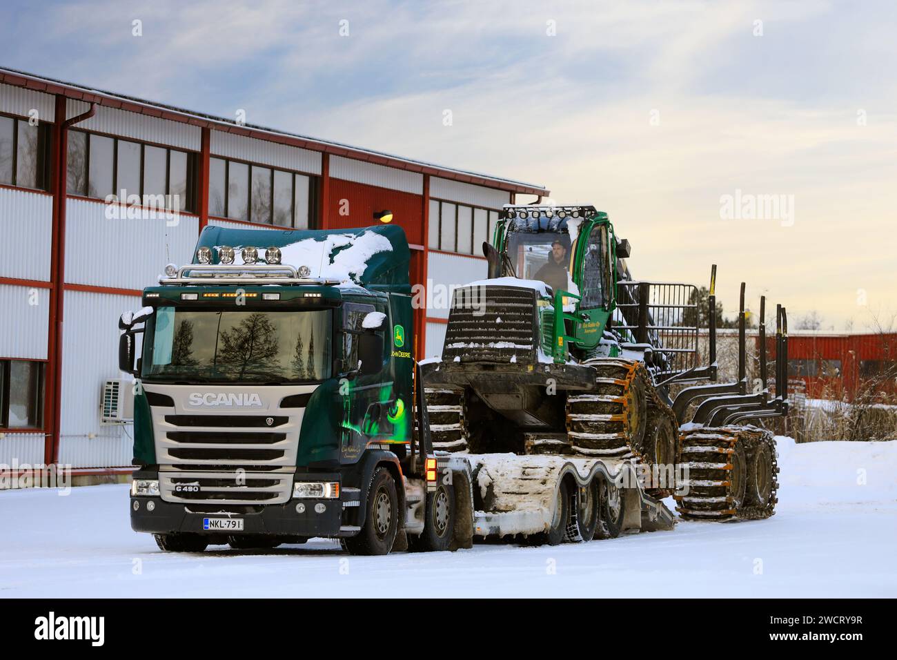 Chargement du porteur forestier John Deere 1210E sur la remorque Scania G490 pour le transport un jour d'hiver. Salo, Finlande. 27 décembre 2023. Banque D'Images