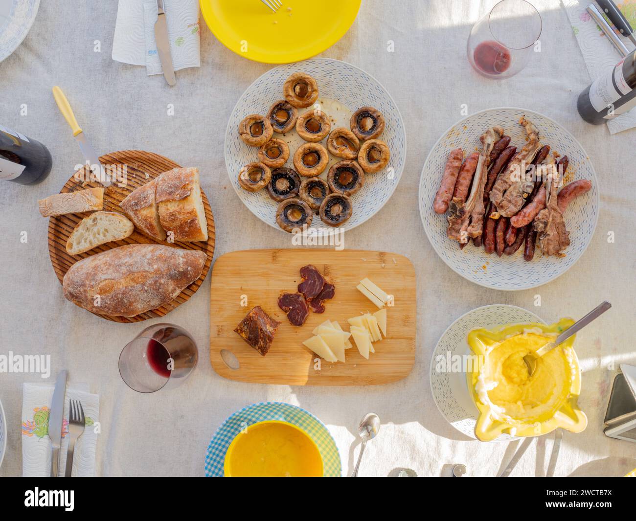 Plat de table servi avec des assiettes de champignons hot-dog sauce viande grillée tranches de bouteilles de pain et tasses de boissons et cuillères à fourchette et couteaux Banque D'Images