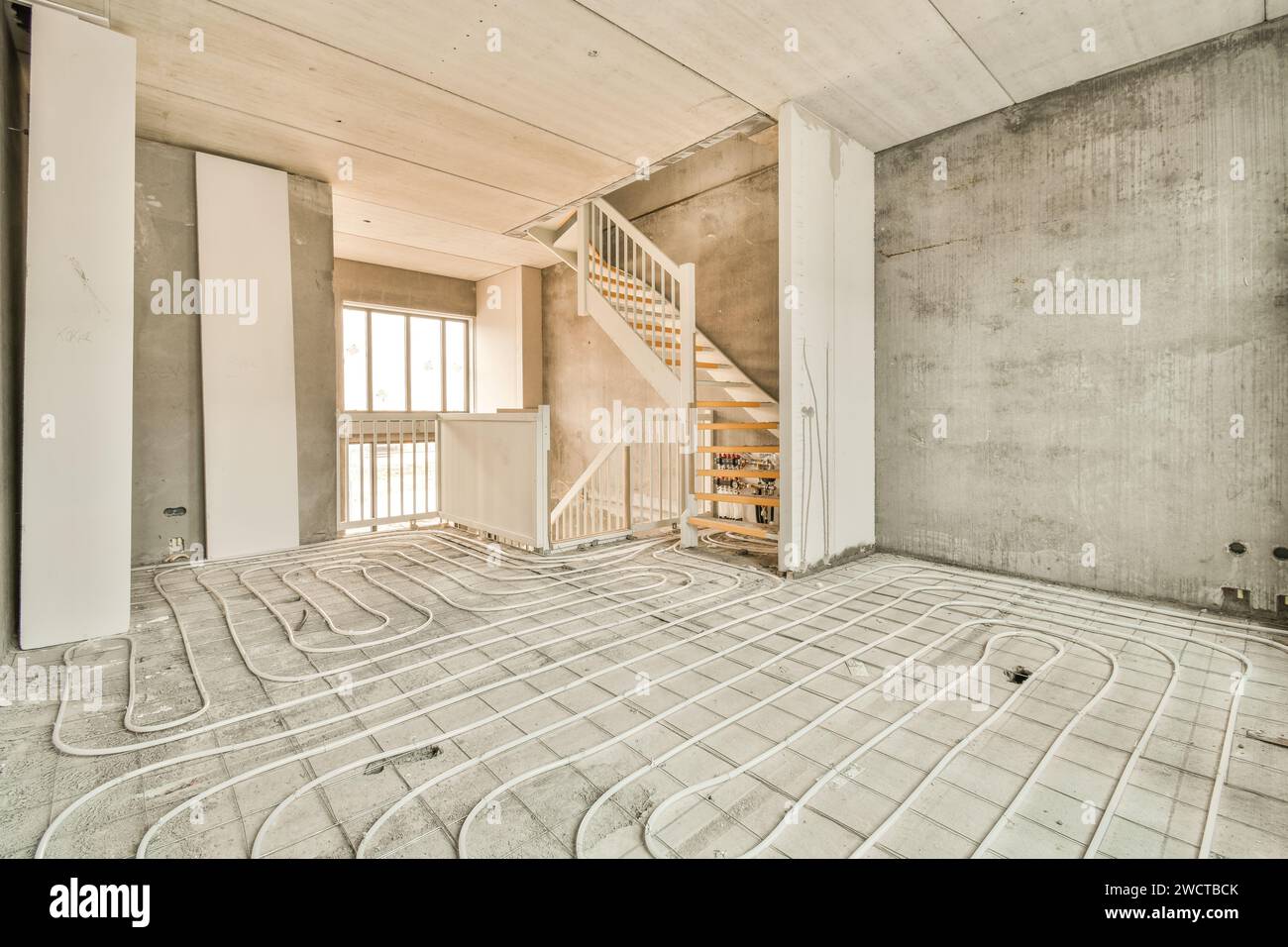 l'intérieur d'une maison en construction avec des tuyaux traversant le sol et des escaliers menant au deuxième étage Banque D'Images