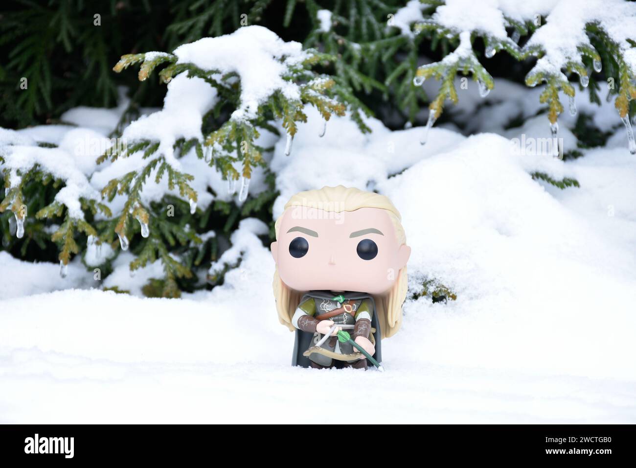 Funko Pop figurine d'action d'elfe Legolas du film fantastique le Seigneur des anneaux. Guerrier tenant arc et flèche. Forêt d'hiver, neige, bois vert. Banque D'Images