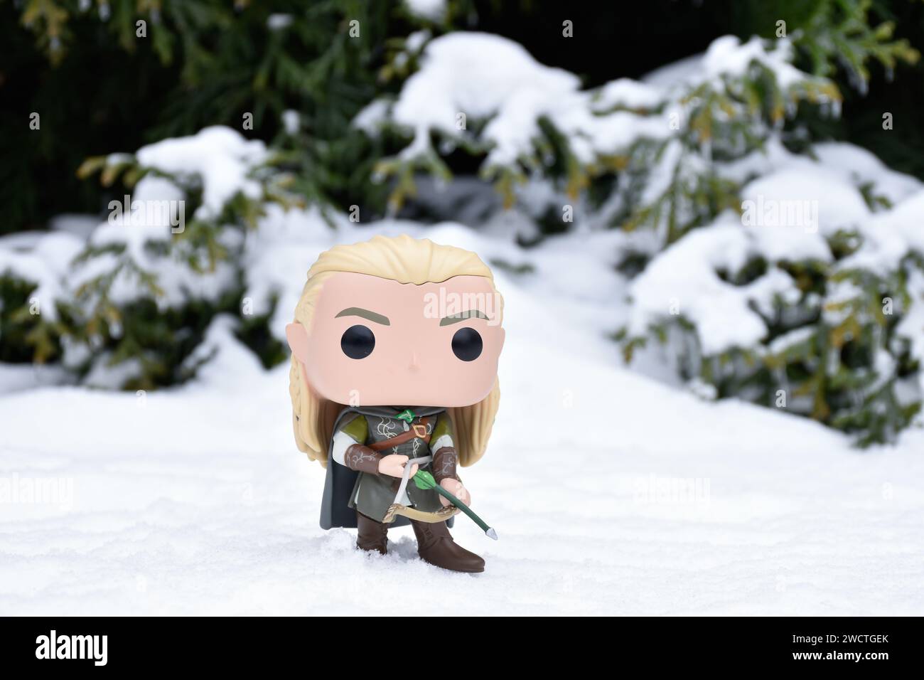 Funko Pop figurine d'action d'elfe Legolas du film fantastique le Seigneur des anneaux. Guerrier tenant arc et flèche. Forêt d'hiver, neige, bois vert. Banque D'Images