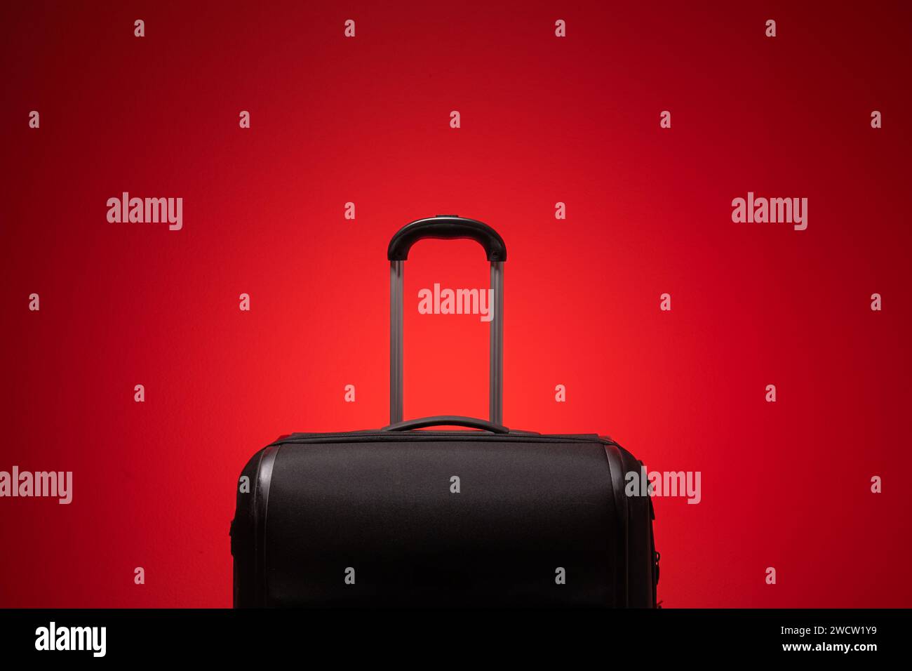 Valise de voyage noir avec poignée de maintien en métal isolé à nouveau fond rouge. Gros plan en studio, pas de gens. Banque D'Images