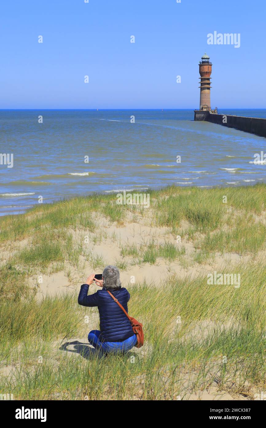 France, Nord, Dunkerque, touriste photographiant dans les dunes avec en arrière-plan l'incendie de Saint-Pol (1937) par l'architecte Gustave Umbdenstock sur la jetée ouest du port Banque D'Images