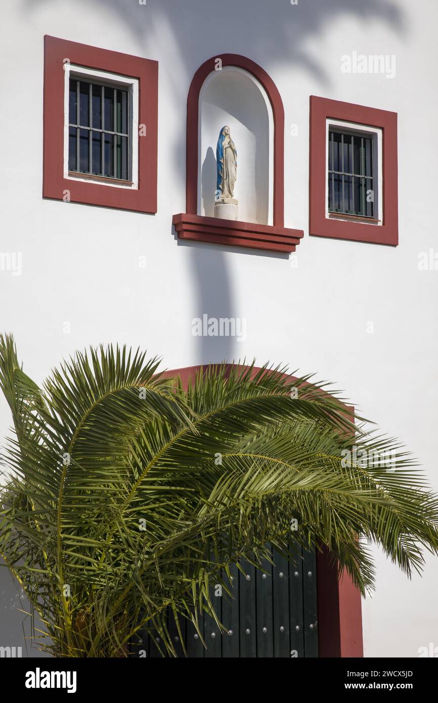 Espagne, Andalousie, Moron de la Frontera, Hacienda las Alcabalas, vierge placée dans une niche et un palmier sur la façade blanche d'une Hacienda de style sévillien Banque D'Images