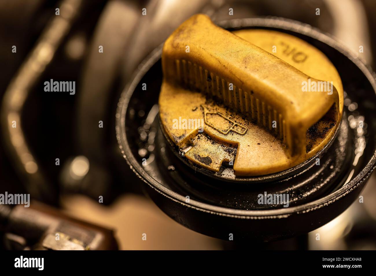 La photo montre un bouchon d'huile sale sur un moteur de voiture, symbolisant le besoin urgent d'entretien du véhicule. Banque D'Images