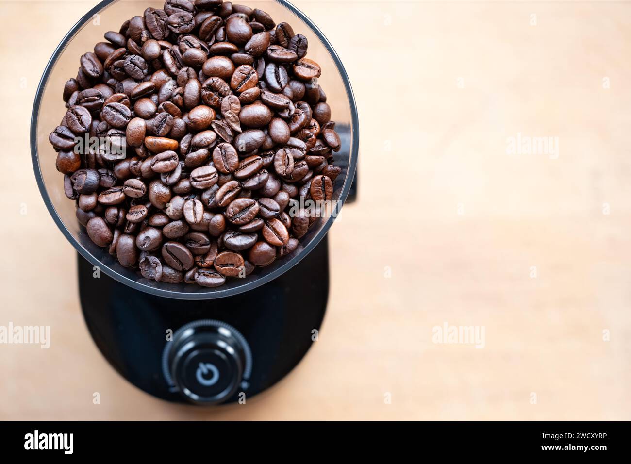 L'invention concerne un moulin à café électrique domestique rempli de grains de café torréfiés entiers attendant d'être moulus pour faire du café frais Banque D'Images