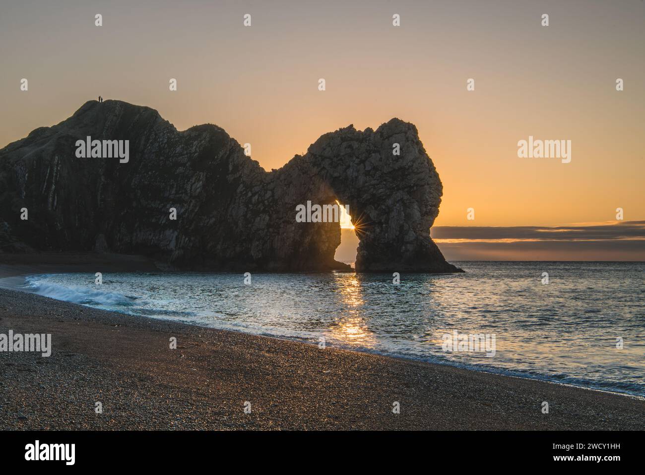 Durdle Door pendant la Solstice d'hiver lorsque le soleil se lève à travers la voûte. Banque D'Images