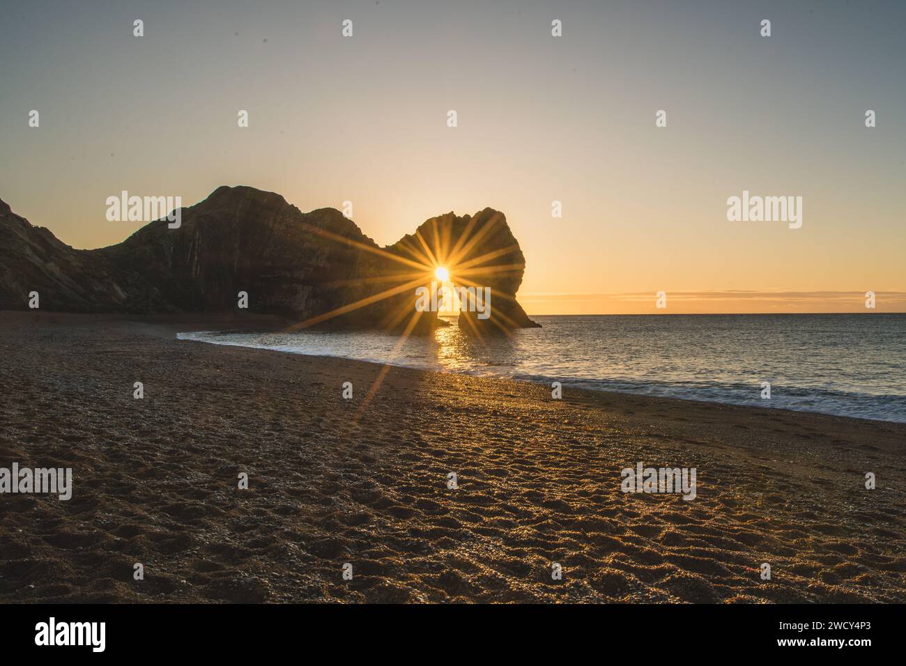 Durdle Door pendant la Solstice d'hiver lorsque le soleil se lève à travers la voûte. Banque D'Images