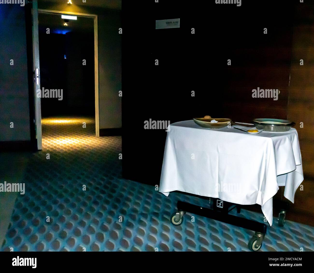 Chariot de ménage avec vaisselle sale dans un couloir d'hôtel. Nettoyage du chariot de la femme de ménage d'accueil avec assiettes de vaisselle finies à côté de l'entrée de la chambre Banque D'Images