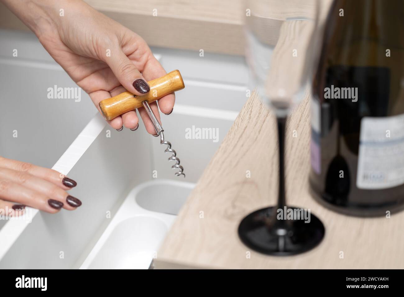 femme tient un tire-bouchon dans sa main pour ouvrir une bouteille de vin. la main d'une femme prend un tire-bouchon dans un tiroir de cuisine. alcoolisme féminin. faible profondeur Banque D'Images