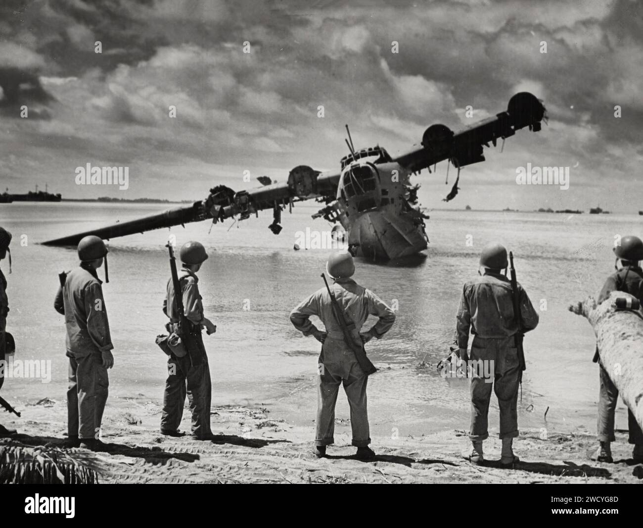 Les troupes de l'armée américaine sont photographiées par un cameraman de combat de la Garde côtière alors qu'elles font une pause dans leur avance pour voir un hydravion japonais pendant la bataille de Makin. L'avion était en réparation dans le lagon lorsque l'invasion a commencé. Les Japonais l'ont utilisé comme nid de mitrailleuses jusqu'à ce que les flics américains s'en occupent. Le photographe est attaché à un transport de combat habité par les garde-côtes opérant dans le cadre d'une force opérationnelle de la Marine. Banque D'Images