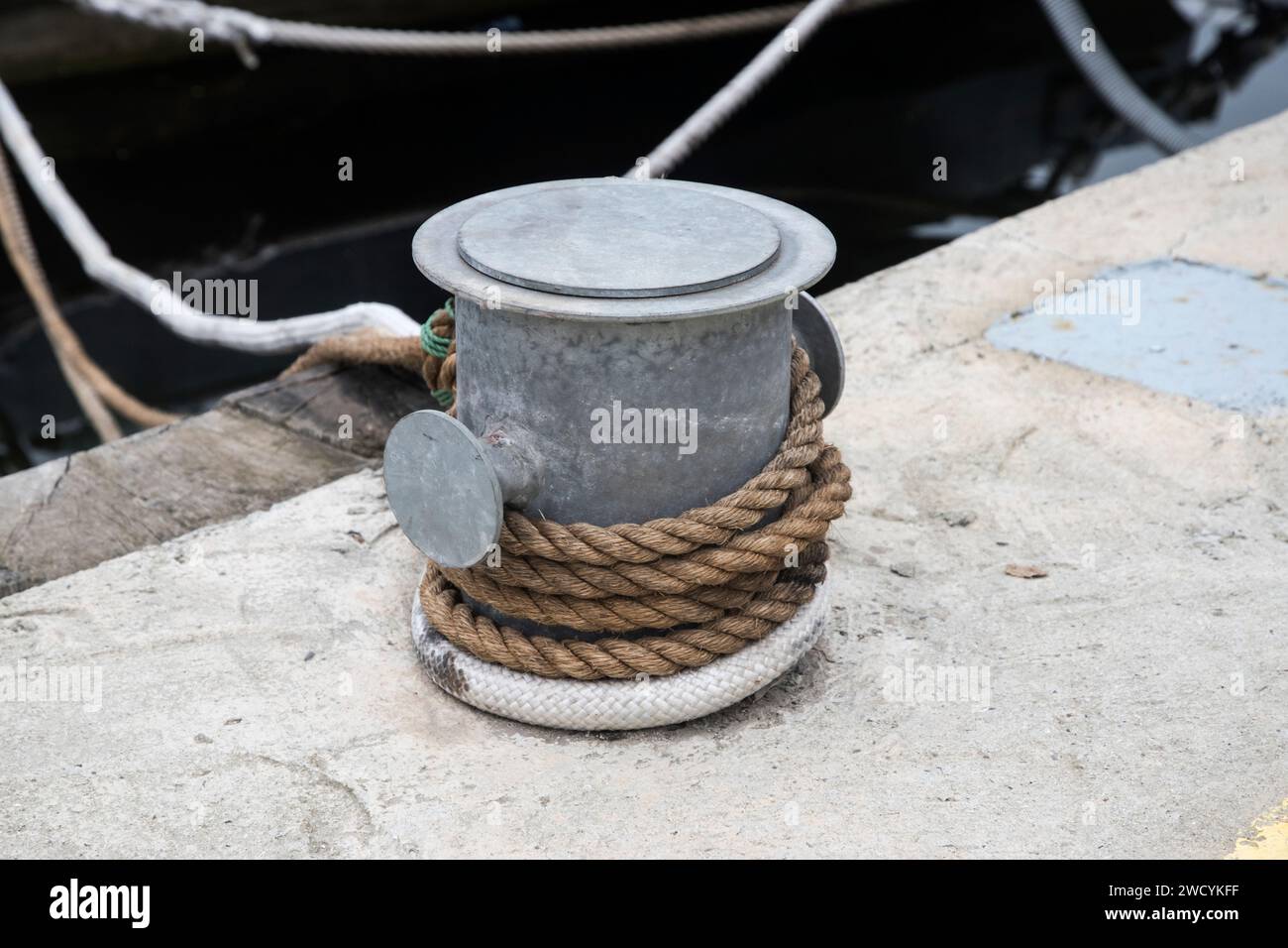 Poteau d'amarrage de quai métallique avec corde pour fixer des bateaux de pêche à proximité Banque D'Images