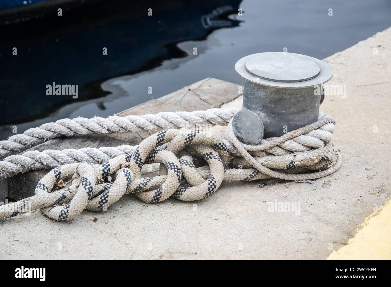 Poteau d'amarrage de quai métallique avec corde pour fixer des bateaux de pêche à proximité Banque D'Images