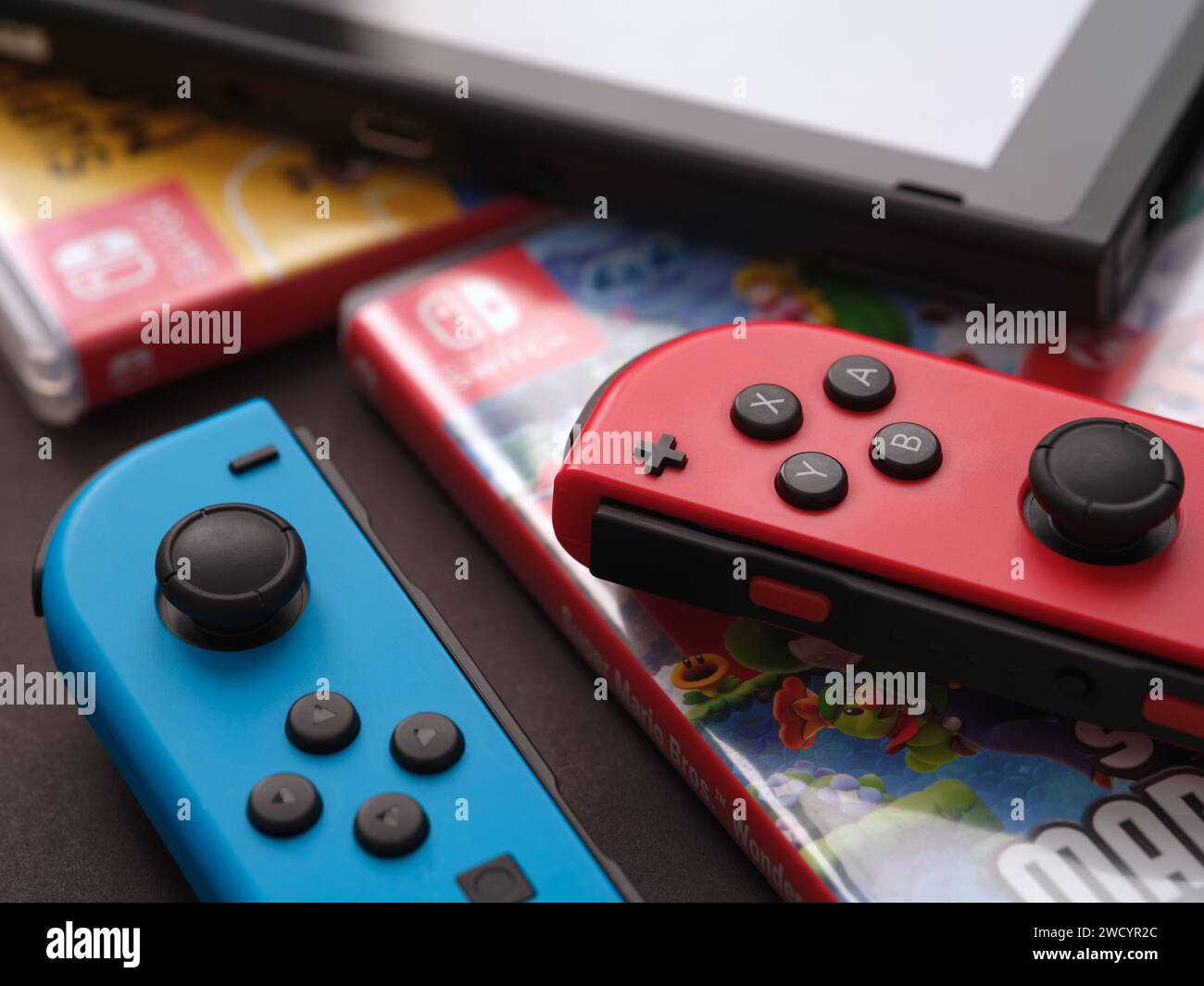 Tambov, Fédération de Russie - 17 janvier 2024 Une console Nintendo Switch avec des joy-cons détachés couchés sur des boîtes de jeu vidéo qui sont couchées sur un su noir Banque D'Images