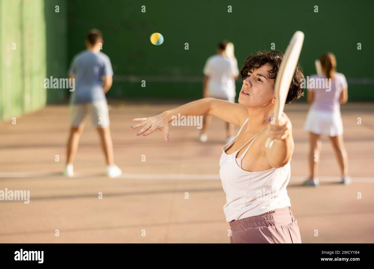 Femme servant le ballon pendant le jeu frontenis à l'extérieur Banque D'Images
