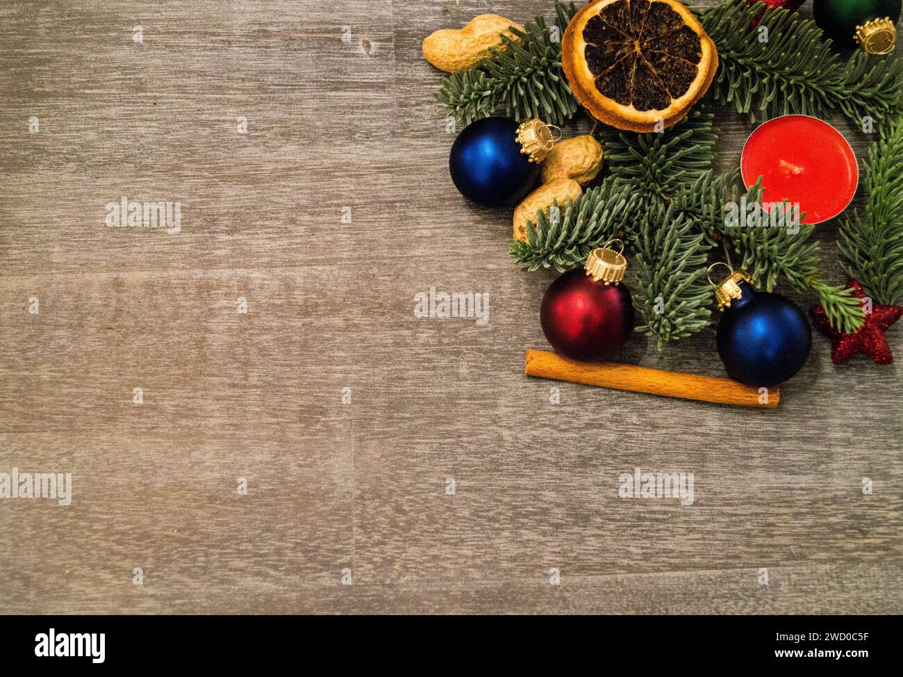 Bougie rouge avec branches de sapin, cacahuètes, étoile, bâton de cannelle, boules d'arbre de Noël et tranches de citron séchées, décorations de Noël Banque D'Images