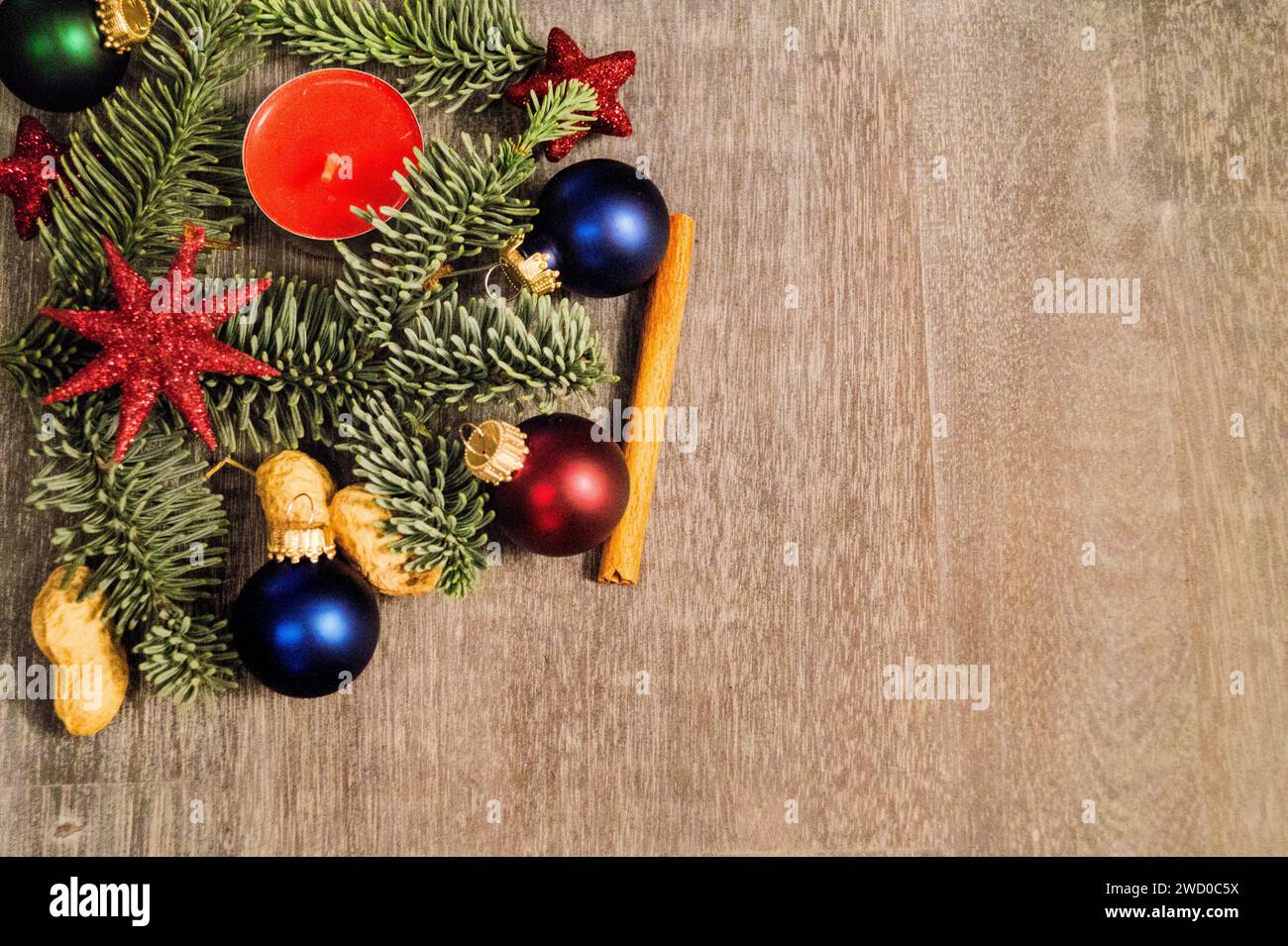 Bougie rouge avec branches de sapin, cacahuètes, étoiles, bâton de cannelle, boules d'arbre de Noël et tranches de citron séchées, décorations de Noël Banque D'Images