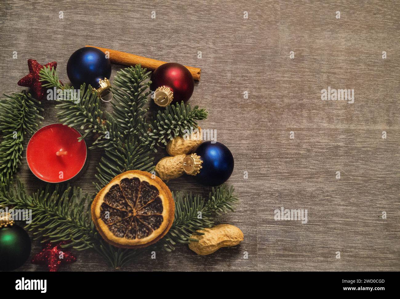 Bougie rouge avec branches de sapin, cacahuètes, étoiles, bâton de cannelle, boules d'arbre de Noël et tranches de citron séchées, décorations de Noël Banque D'Images