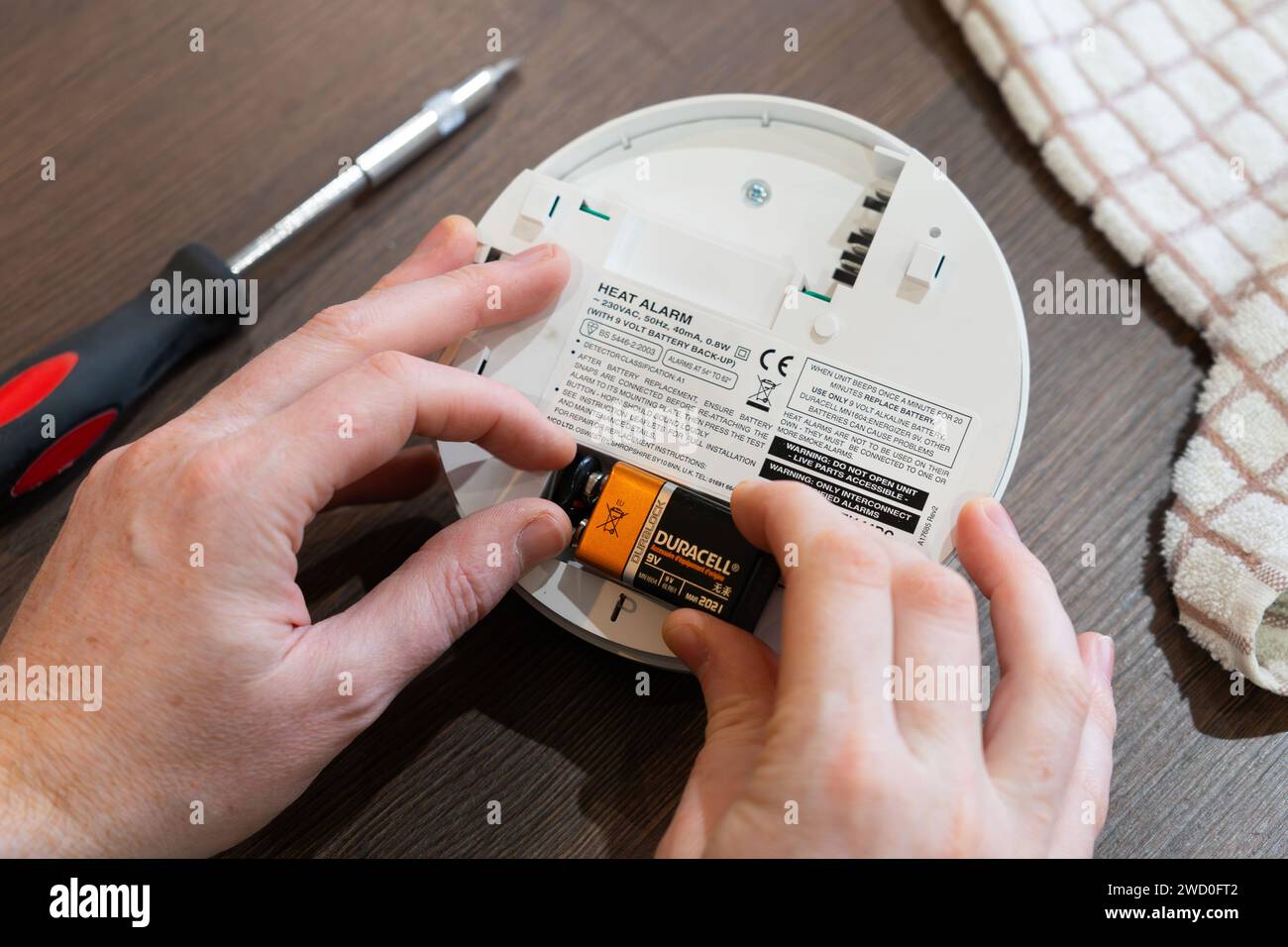 Remplacement de la pile alcaline de secours dans une alarme de chaleur alimentée par secteur EI 144RC (alarme incendie) dans une cuisine après qu'elle a commencé à émettre un bip à partir d'une faible puissance. ROYAUME-UNI Banque D'Images
